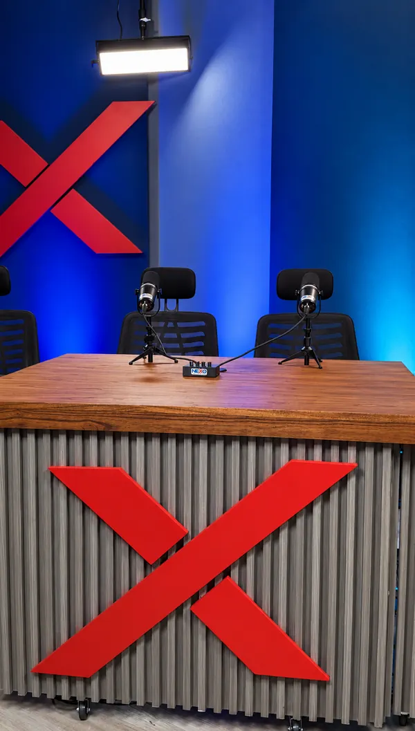 La mesa de conducción de NEXO Studios con la X roja, luz azul y micrófonos